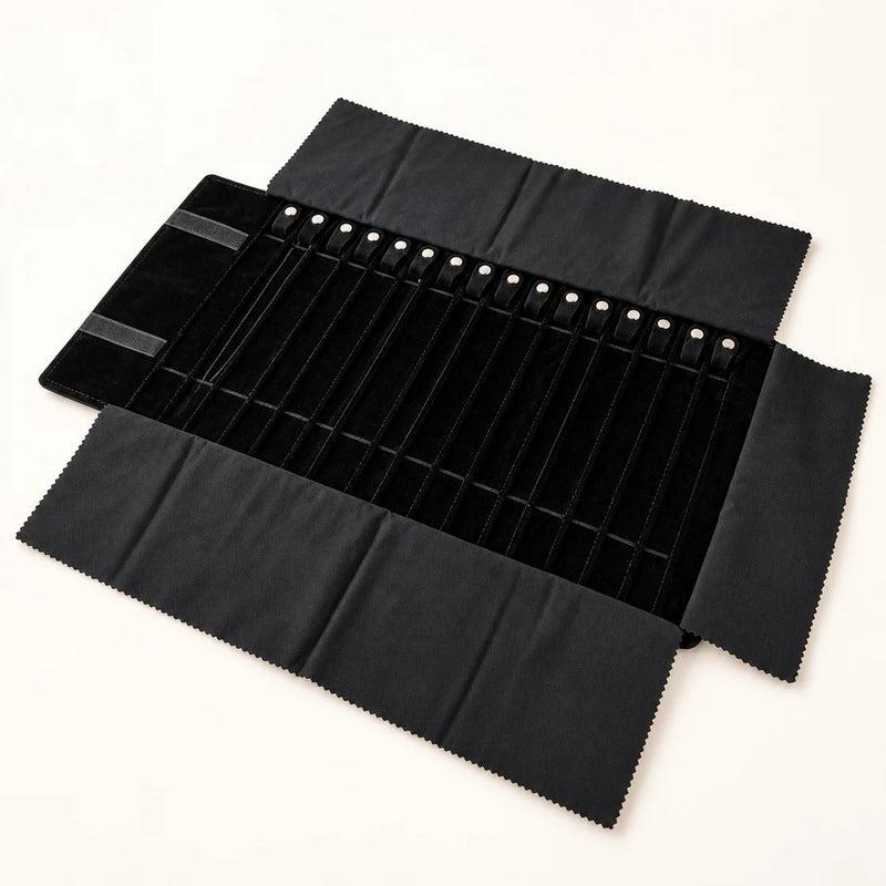 Open black travel jewelry organizer roll on a neutral studio background